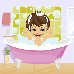 little boy washing his hair with shampoo sitting in bathtub in bathroom