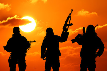 Fototapeta na wymiar three military soldiers silhouetted against a beautiful sunset