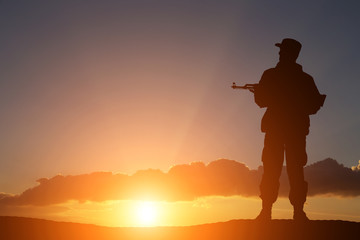 Fototapeta na wymiar silhouette of a soldier with a gun in the sunset
