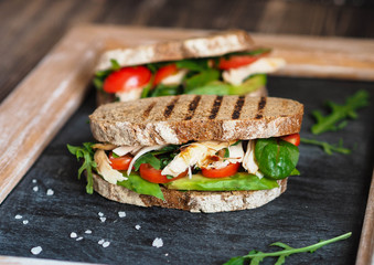 Homemade sandwich with avocado, arugula, tomatoes and grilled chicken
