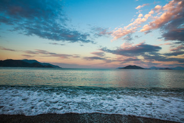 Seascape on background of mountains and sky clouds at dawn