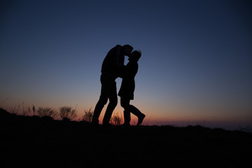 silhouette guy and girl on a beautiful sunset holding hands