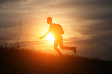 Man runs directly on a hill against a beautiful sunset
