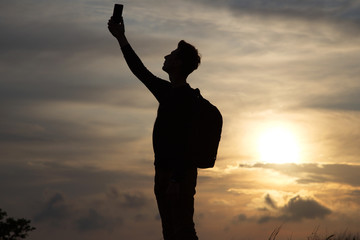 a man standing on a hill looking link on the background of a beautiful sunset