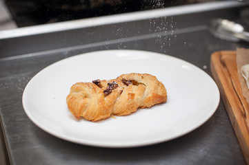 Tasty puff with nuts and sugar powder on plate