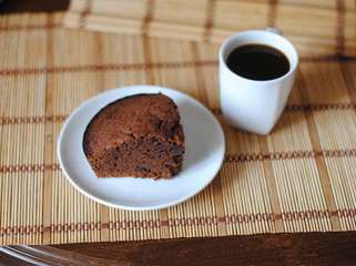 Fototapeta na wymiar A piece of chocolate brownies and coffee in a white bowl on a mat. Close-up