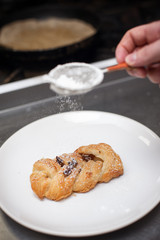 Tasty puff with nuts and sugar powder on plate