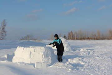 Man building an igloo of snow blocks  on a glade in the winter