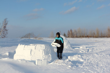 Man building an igloo of snow blocks  on a glade in the winter