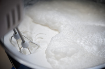 Preparing whipped cream using mixer, closeup