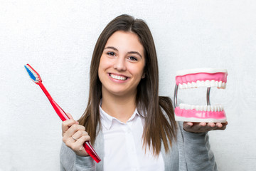 Cute girl holding oversize toothbrush and teeth prosthesis.