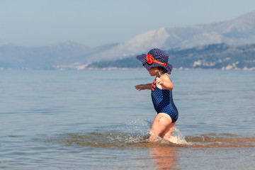 Happy girl in hat and sunglasses, walking near sea