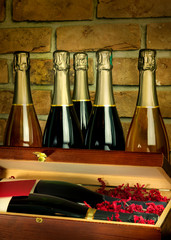 Drewniana skrzynka i butelki szampana na tle ściany z cegły.