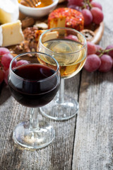 glass of white and red wines, appetizers on a wooden background