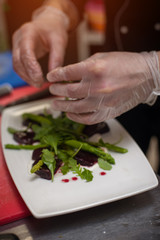 Male chef preparing salad with arugula and beet
