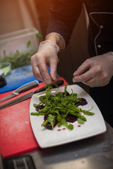 Male chef preparing salad with arugula and beet