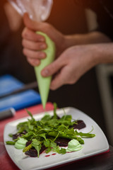 Male chef cooking salad with arugula and beet