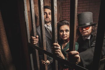 Fototapeta na wymiar Two gentlemen and a lady behind bars in the prison.