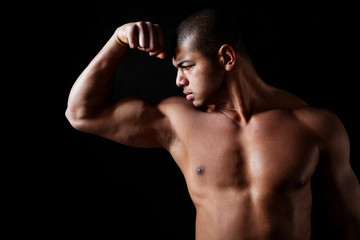 Obraz premium Handsome shirtless african american fitness man standing and showing biceps