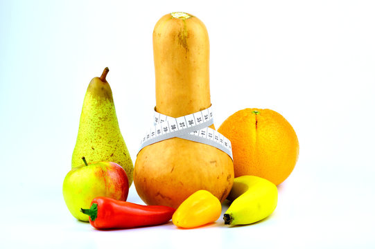 Verschiedenes Obst und Gemüse mit Maßband vor weißem Hintergrund