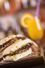 Close up of delicious meat sandwiches. Beautifully served meal at the restaurant. Glass of juice in the background.