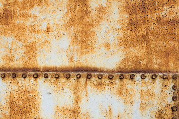 large rusty metal sheet with large bolts, grey and orange colors