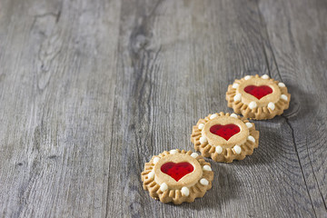 A three cookies with a heart in the middle on the gray wooden background