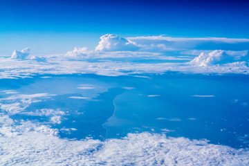 White clouds and blue sky seen from the window of an airplane.