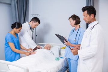 Doctors examining patient in ward