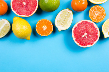 Several kinds of whole and cut citrus on a blue background