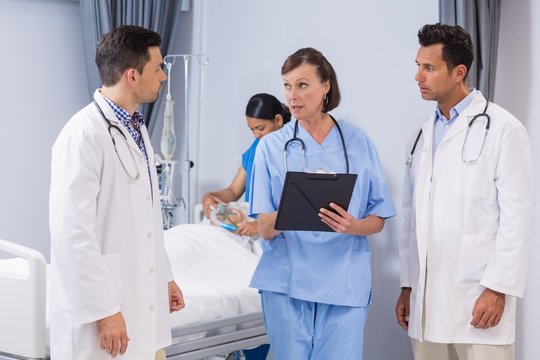 Portrait of doctors and nurse discussing medical report