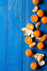 Whole, cutted and pilled mandarins on a blue painted wooden background