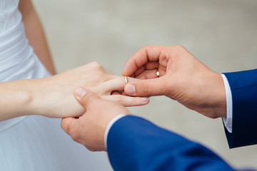Closeup of groom placing ring on brides finger on their