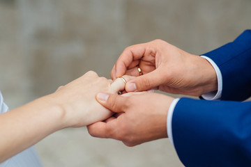 Closeup of groom placing ring on brides finger on their