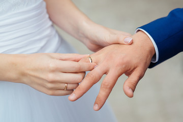 Closeup of groom placing ring on brides finger on their