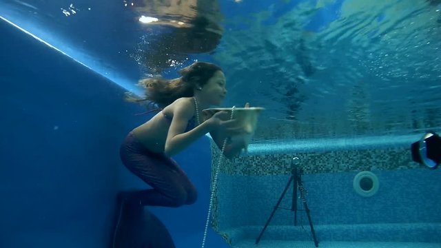 girl in mermaid costume wearing poses underwater in swimming pool