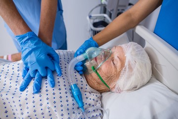 Doctor and nurse treating senior patient in ward