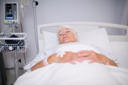 Senior woman patient wearing oxygen mask lying on bed 