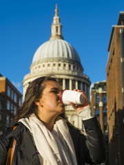 Eine junge Frau trinkt aus einem Becher Kaffee, hinten St. Paul's Cathedral, anglikanische...