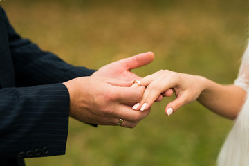 Closeup of groom placing ring on brides finger on their