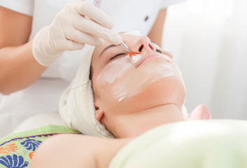 Obraz na płótnie Canvas Facial mask.Beautiful young woman getting facial treatment in beauty salon