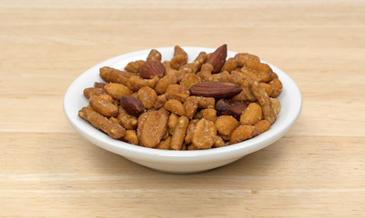 Energy trail mix blend in a small bowl atop a wood table. 