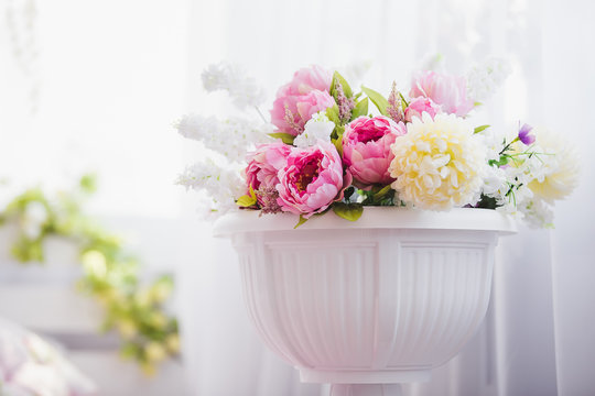 Pink and white flowers in a vase near the bed