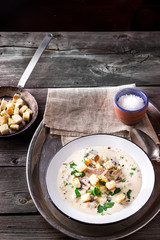 Cheese soup with croutons in white bowl.