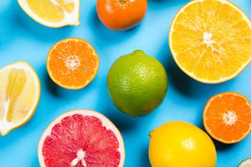 Several kinds of whole and cut citrus on a blue background