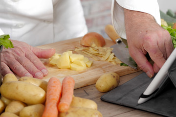detail of hands of chef using tablet for cooking