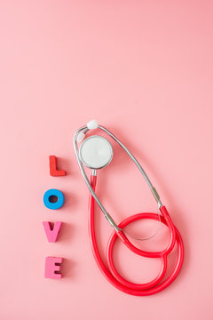 Stethoscope with love on pink background.