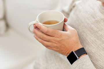 close up of senior man with tea and wristwatch