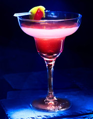 Soft drink glass with pomegranate juice on black background. Cocktail decoration lemon and cherry.