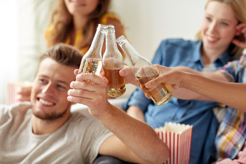 happy friends clinking beer bottles at home party